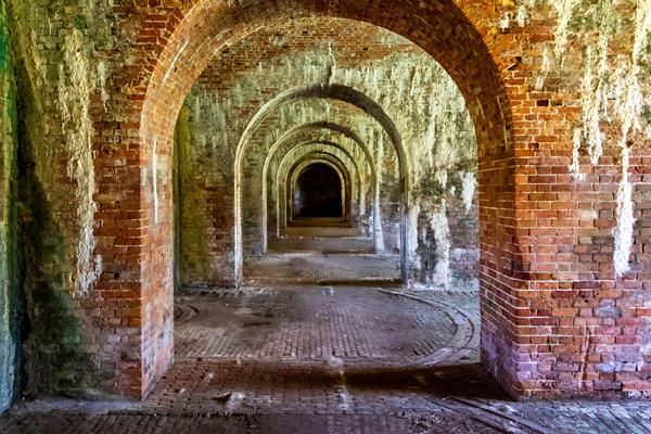 Brick archway tunnel in an abandoned structure, arches receding into darkness.
